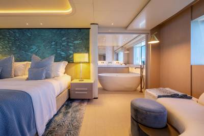A luxurious bedroom with a king-sized bed in the foreground and a modern bathroom with a freestanding tub in the background.
