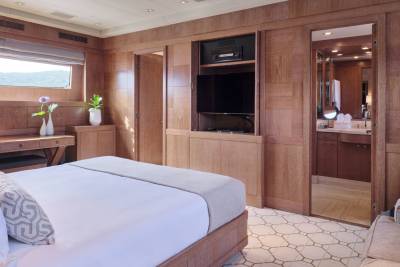 A luxurious bedroom with a large bed in the foreground and a glimpse into a well-lit bathroom in the background.