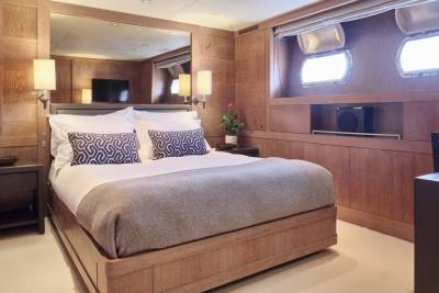 A luxurious bedroom with a large bed in the foreground and a desk and windows in the background.