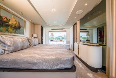 A luxurious bedroom with a large bed in the foreground and a window with a scenic view in the background.