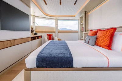 A luxurious bedroom with a large bed in the foreground and a scenic view through the windows in the background.