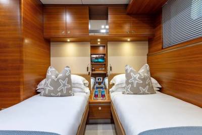 Two twin beds with starfish-patterned pillows are in the foreground, while the background features wood-paneled walls and cabinetry.