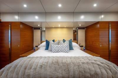 A luxurious bedroom with a plush blanket in the foreground and wood-paneled walls and mirrored cabinets in the background.