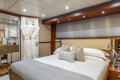 A luxurious bedroom with a plush bed in the foreground and a modern bathroom with plush robes in the background.