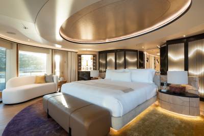 A luxurious bedroom with a plush king-sized bed in the foreground and a modern, illuminated bar area in the background.
