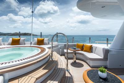 A luxurious yacht's deck features a bubbling jacuzzi in the foreground and a serene ocean view with distant islands in the background.