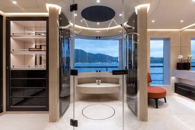 A luxurious bathroom with a walk-in closet on the left and a scenic ocean view through a glass-enclosed shower in the background.