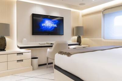 A luxurious bedroom with a large bed in the foreground and a television mounted on the wall in the background.