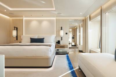 A luxurious bedroom with a large bed in the foreground and a hallway with a mirror in the background.