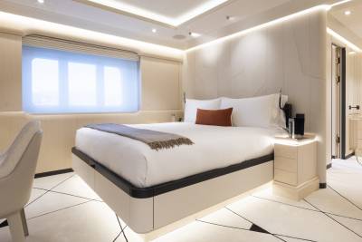 A luxurious bedroom with a floating bed in the foreground and a dresser and doorway in the background.