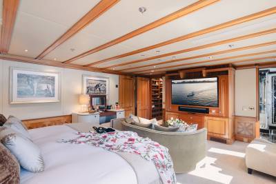 A luxurious bedroom with a large bed in the foreground and a television and seating area in the background.