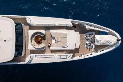 A luxurious white yacht with a spacious deck and seating areas floats on the deep blue ocean.