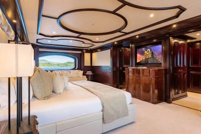 A luxurious bedroom with a large bed in the foreground and a television screen in the background, all set within a richly decorated interior.
