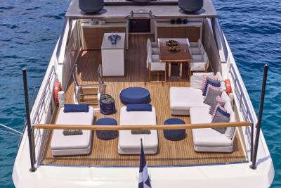 A luxurious yacht deck with lounge chairs and a dining area sits on the clear blue ocean.
