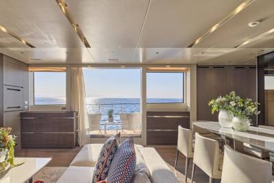 A luxurious yacht interior with a plush sofa in the foreground and a panoramic ocean view through large windows in the background.