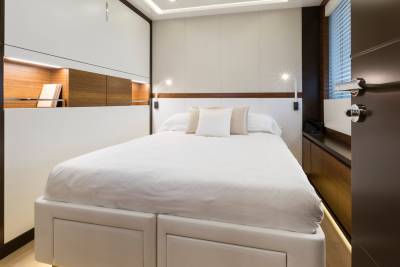 A neatly made white bed with pillows dominates the foreground, while the background reveals a modern cabin with wooden accents and a window.