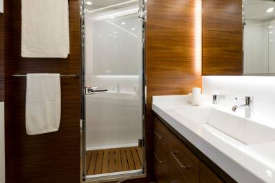 A modern bathroom with a wooden shower stall in the background and a white double vanity in the foreground.