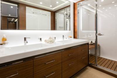 A modern bathroom with a double vanity in the foreground and a glass-enclosed shower in the background.