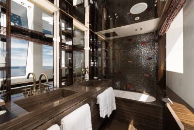 A luxurious bathroom with a double vanity in the foreground and a mosaic-tiled bathtub with a view of the ocean in the background.
