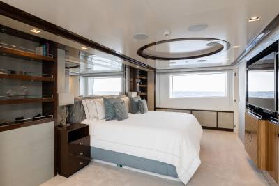 A luxurious bedroom with a large bed in the foreground and a window overlooking the ocean in the background.