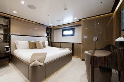 A luxurious bedroom with a large bed in the foreground and a desk and wardrobe in the background.
