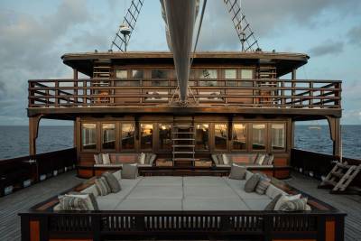 A spacious, cushioned deck with a wooden superstructure and a calm ocean in the background.