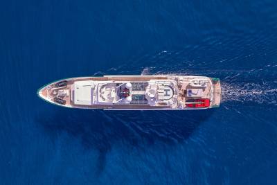A luxurious white yacht cruises through the deep blue ocean, leaving a white wake behind it.