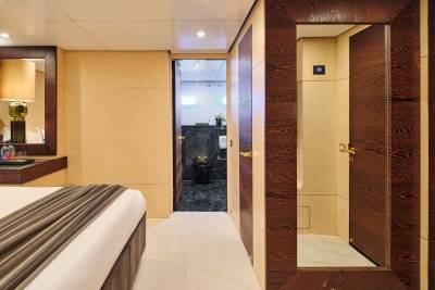 A luxurious bedroom with a bed in the foreground leads to a modern bathroom in the background.