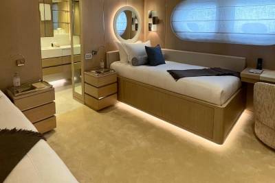 Two beds with plush carpeting in the foreground lead to a modern bathroom with mirrored walls and sleek cabinetry in the background.