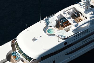 A luxurious white yacht with a jacuzzi on its deck floats on dark blue water.