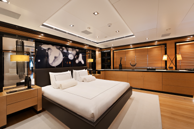 A luxurious bedroom with a large bed in the foreground and wooden cabinets and blinds in the background.