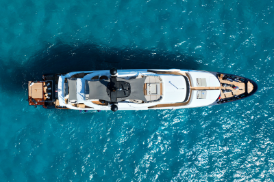 A luxurious white yacht with dark accents floats on the clear turquoise ocean.