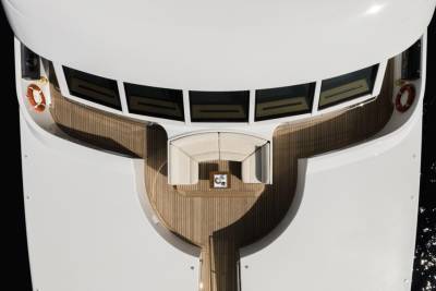 A luxurious white yacht with a wooden deck and seating area is docked in dark water.