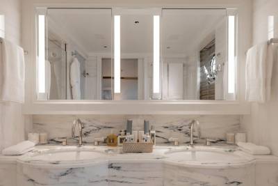 A luxurious marble double vanity with toiletries sits below a large mirror reflecting a well-lit bathroom.