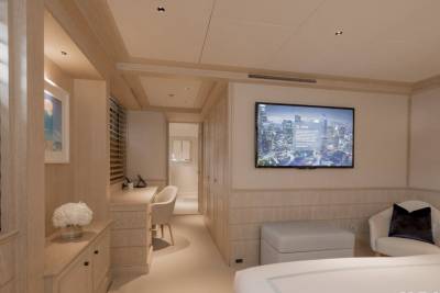 A modern bedroom with a desk and chair in the foreground and a large television mounted on the wall in the background.