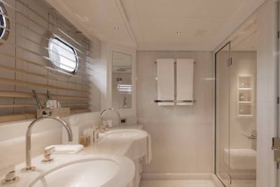 A luxurious bathroom with dual sinks in the foreground and a glass-enclosed shower in the background.