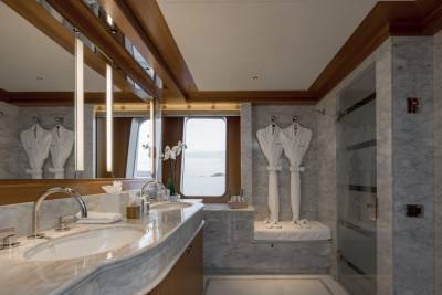 A luxurious bathroom with marble countertops and plush robes in the foreground, and a window with a view of the ocean in the background.
