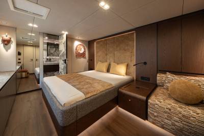 A luxurious bedroom with a plush bed in the foreground and a modern bathroom visible in the background.