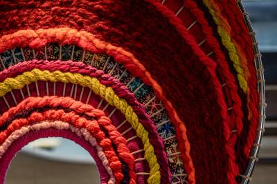 A close-up of a colorful woven tapestry with a blurred background of what appears to be a window.