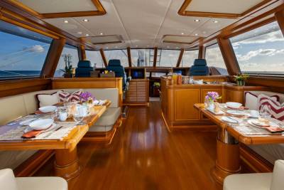 Luxurious wooden dining tables are set for meals in the foreground, while the background reveals a panoramic view of the ocean through large windows.