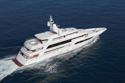 A large white luxury yacht cruises through deep blue ocean waters, leaving a white wake in its path.