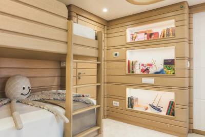 A set of light-wood bunk beds with a plush octopus toy in the foreground sits beside a wall of built-in recessed bookshelves in the background.