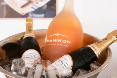 Three bottles of champagne and rosé wine sit chilled in a metal ice bucket against a plain white background.