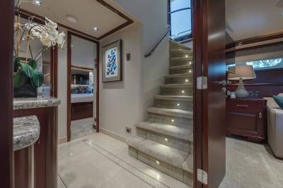 A luxurious interior features a carpeted staircase with built-in lighting in the center, flanked by a kitchen area with white flowers in the foreground and a cozy living space in the background.