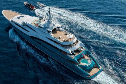 A luxurious yacht glides through the deep blue ocean, leaving a trail of white foam in its wake.