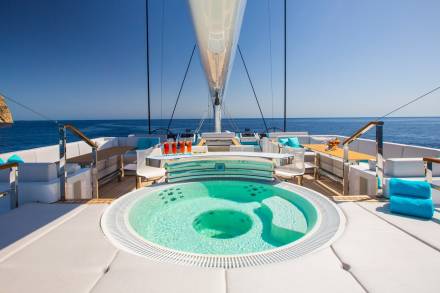 Relax in the turquoise waters of this yacht's jacuzzi, surrounded by the stunning blue sea and a rugged coastline.