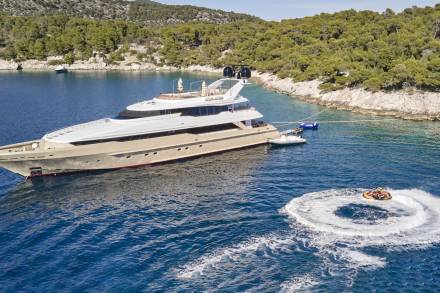 A luxurious yacht anchors in a secluded cove while guests enjoy a thrilling ride on a jet ski.