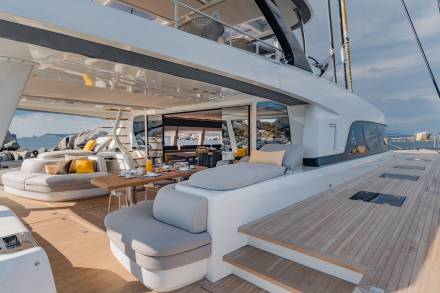 A luxurious yacht deck offers a serene breakfast setting with a view of rocky islands under a cloudy sky.