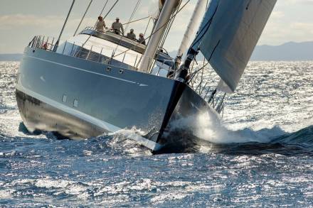 A sleek yacht cuts through choppy, sun-dappled waves, its crew expertly navigating the open sea.