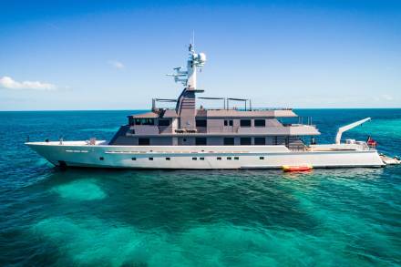 A luxurious yacht floats serenely in the crystal-clear turquoise waters under a brilliant blue sky.